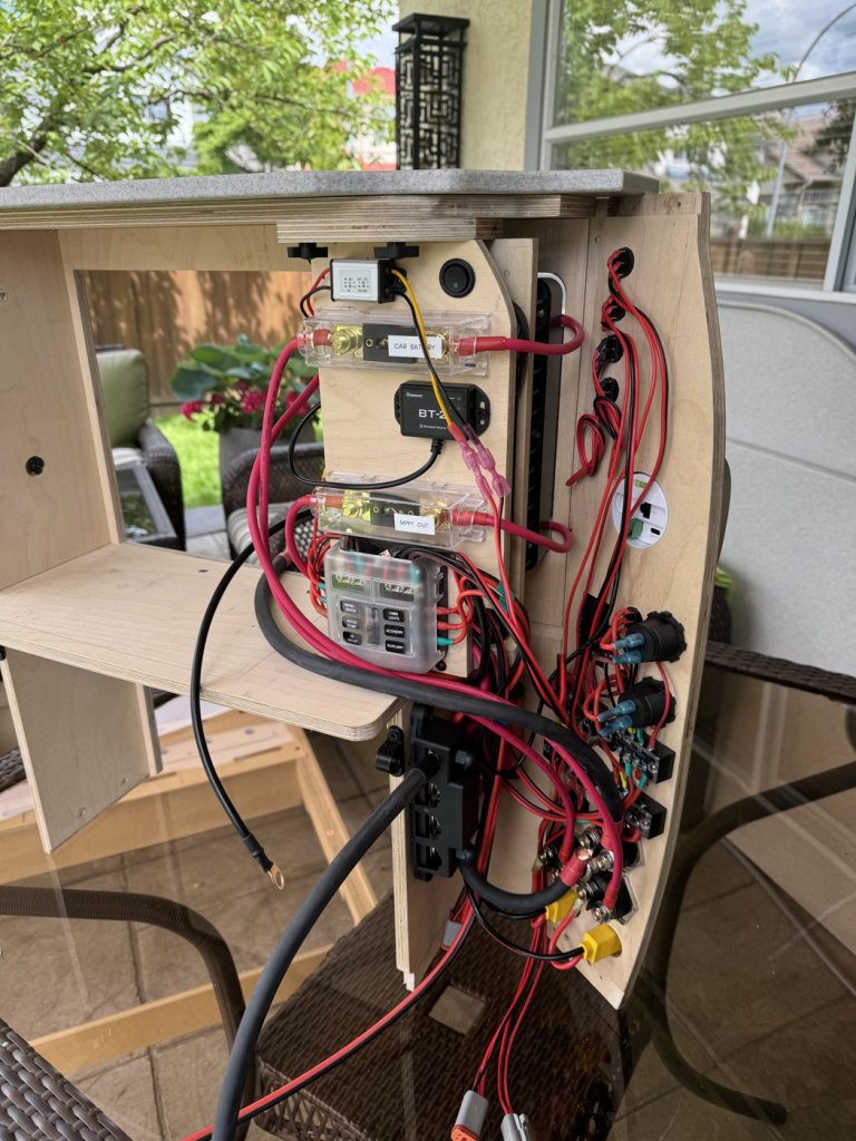 Back of the removable charger frame showing labeled fuses, Renogy Bluetooth module, fuse block and wiring for a minivan camper electrical system