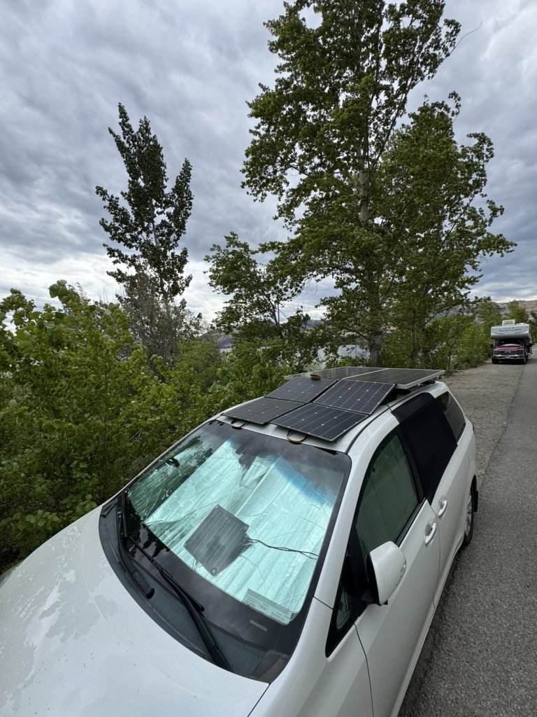 Small solar trickle charger lying on the dashboard sunshade of a Toyota Sienna to maintain the starter battery